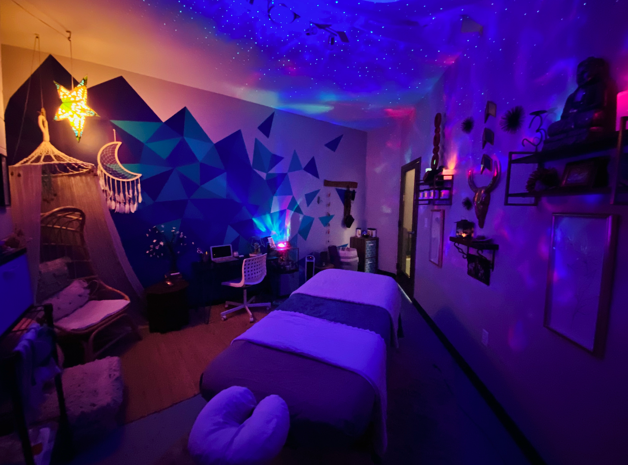 Vital Kneads treatment room with ambient galaxy lighting, massage table, and calming holistic d&eacute;cor